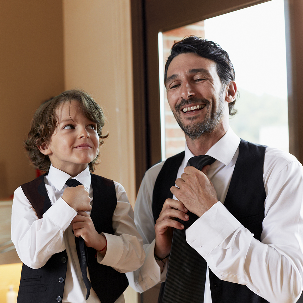 Son copying father in putting on a tie