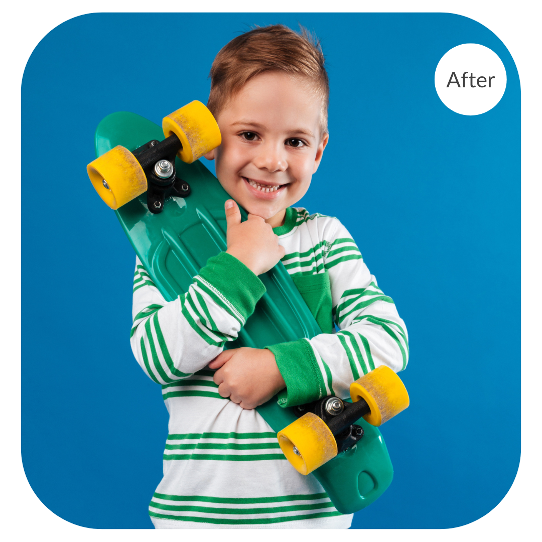 Studio portrait of a boy holding a skateboard against a blue background before the image is color corrected